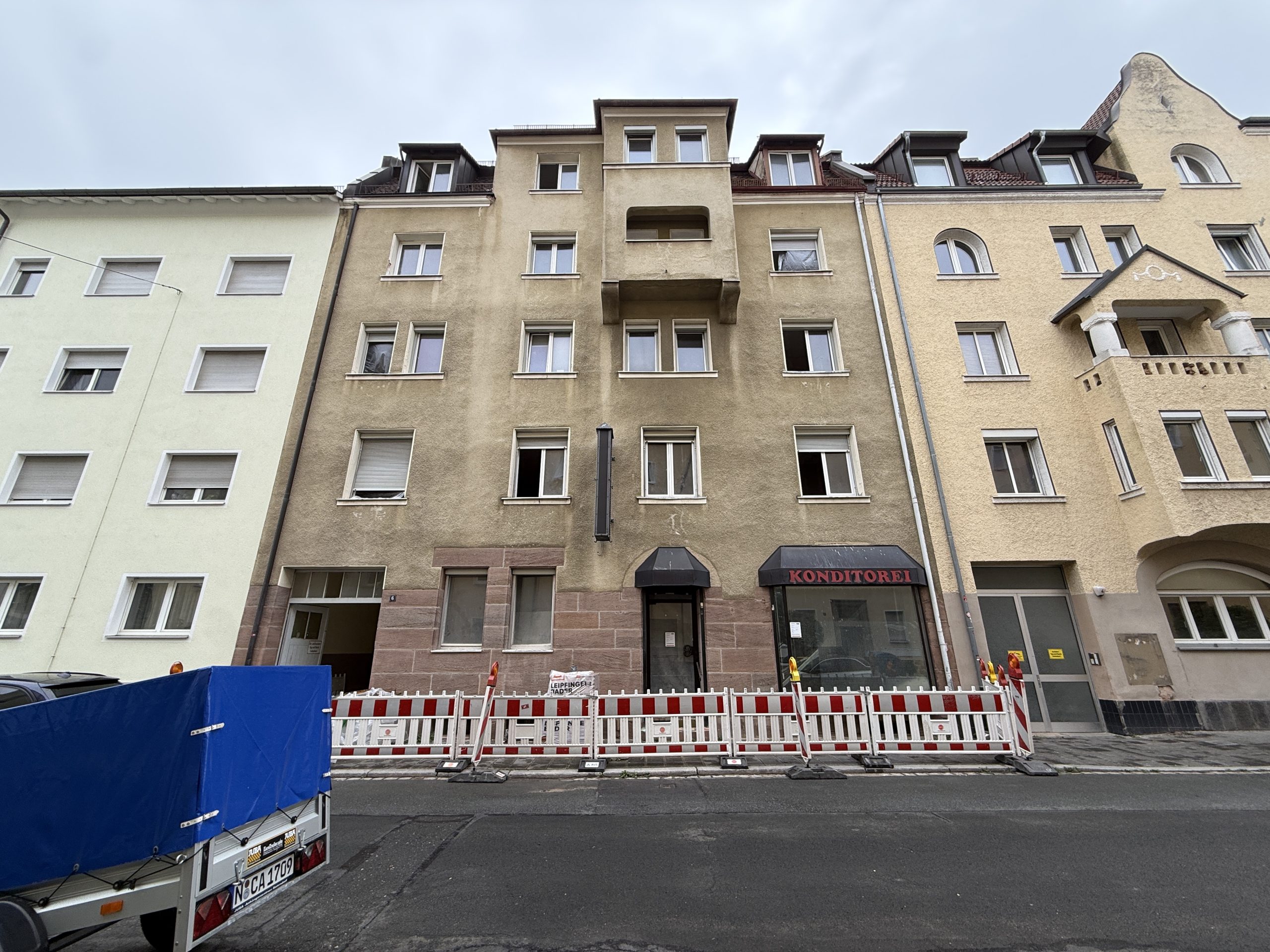 Mehrfamilienhaus – Außenansicht Straßenansicht eines Mehrfamilienhauses mit abgesperrtem Baustellenbereich